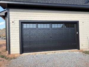 black carriage style garage door with decorative handles and upper windows on new construction home in cornelius