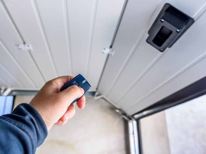 garage door repair man holding opener to sensor